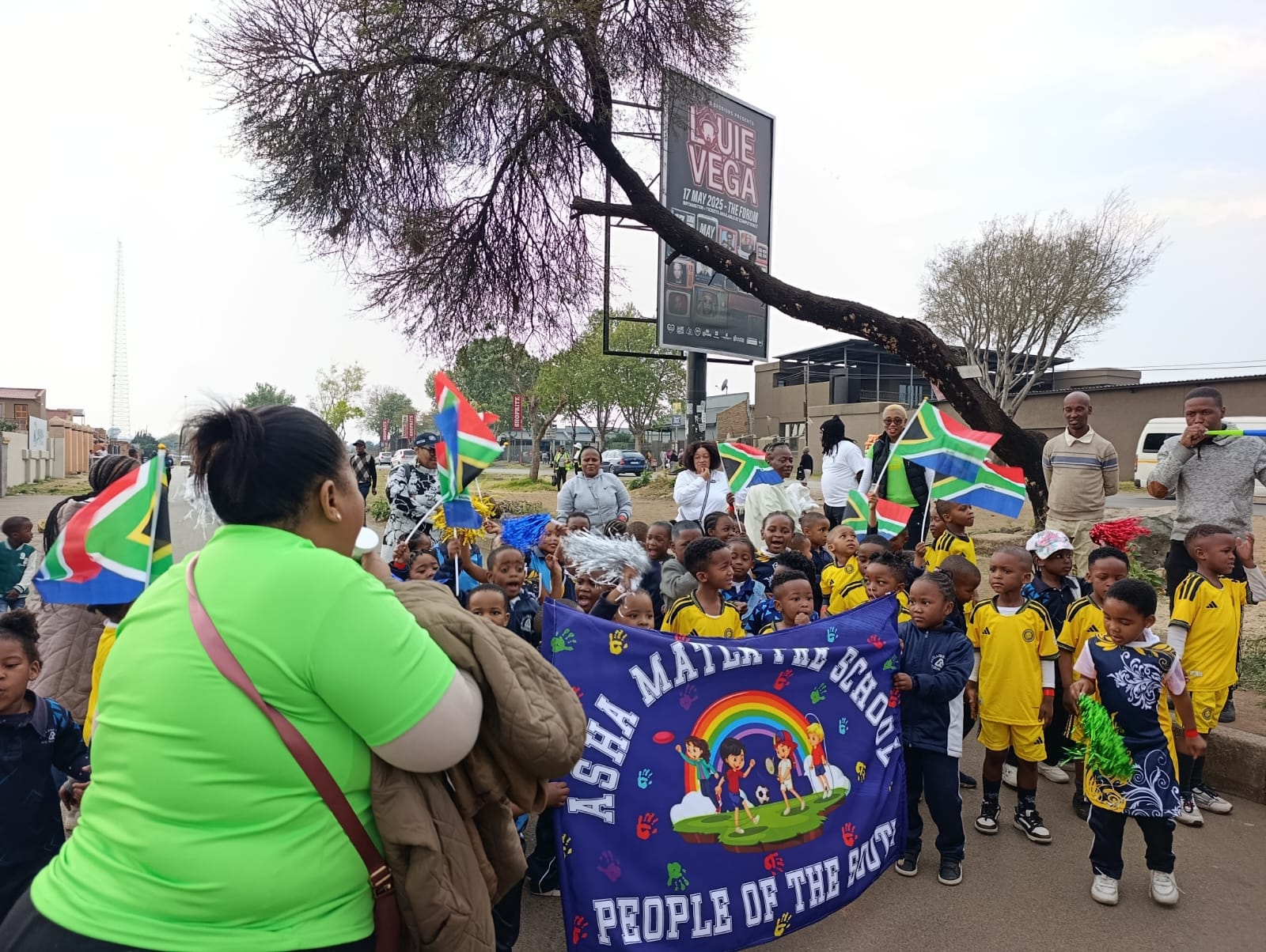Matla Pre School learners and staff marching in a community parade with South African flags